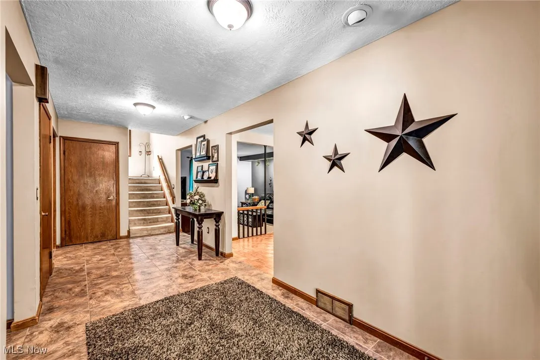 Hall featuring a textured ceiling and stairs