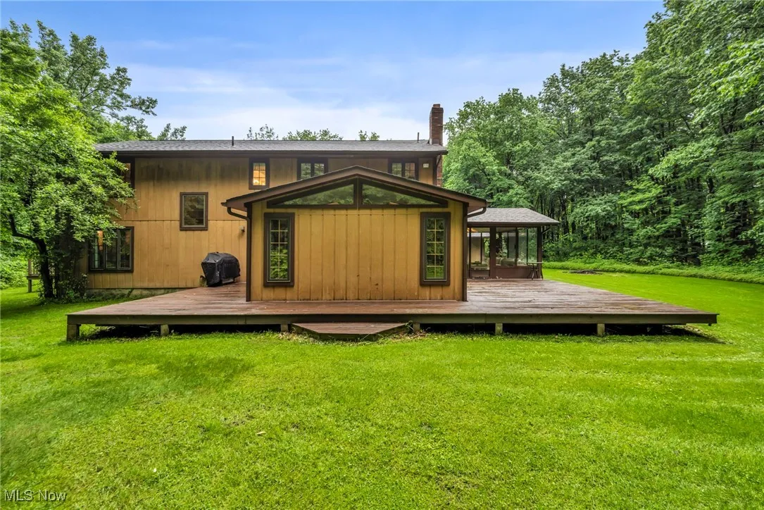 Rear view of property featuring a wooden deck and a yard