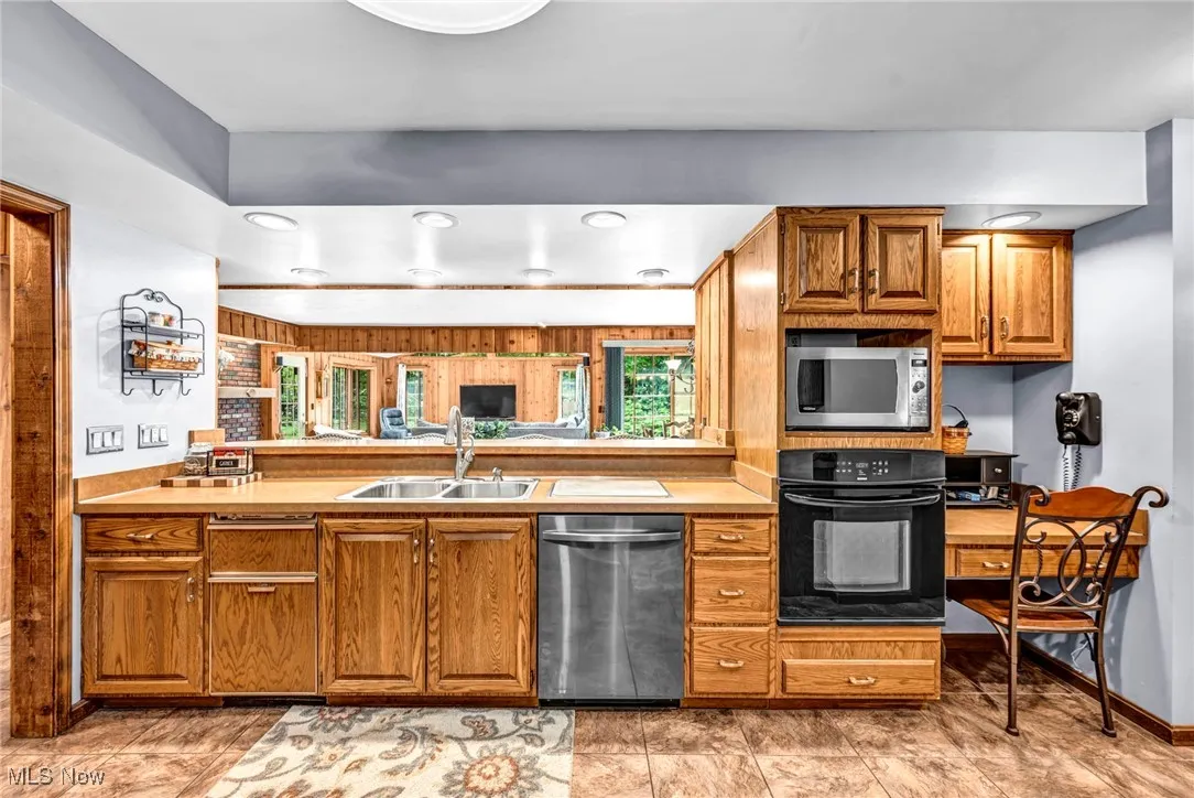 Kitchen with appliances with stainless steel finishes, brown cabinetry, a peninsula, recessed lighting, and light countertops