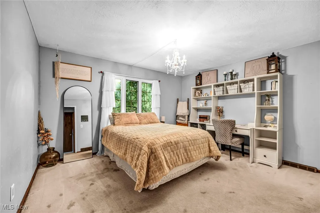 Bedroom featuring carpet flooring, a chandelier, arched walkways, and a textured ceiling