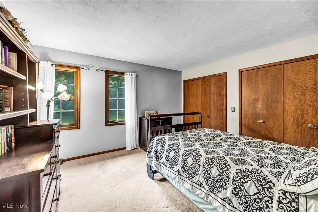 Bedroom with multiple closets, light carpet, and a textured ceiling