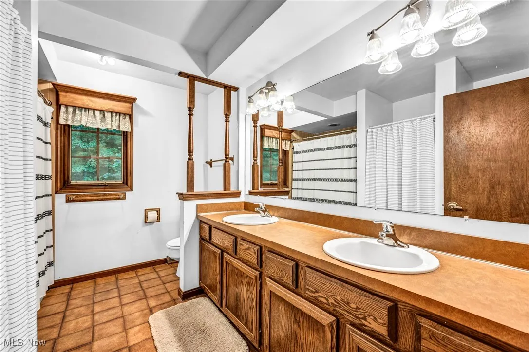 Full bath with double vanity, curtained shower, and tile patterned flooring