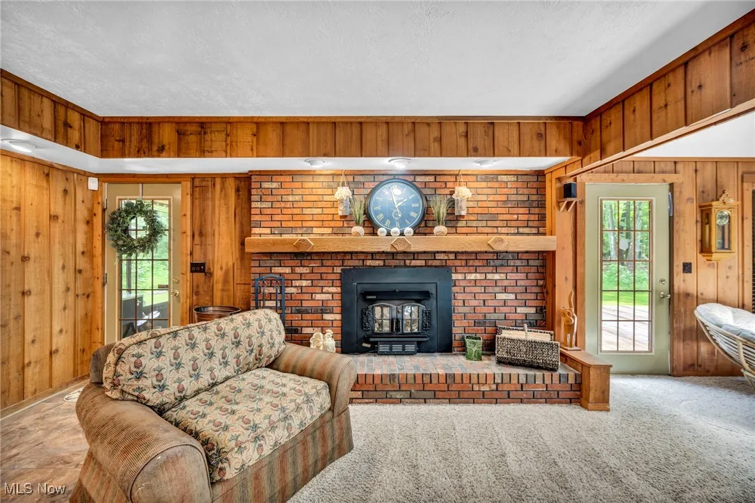 Carpeted living area featuring wood walls, a wood stove, healthy amount of natural light, and a textured ceiling