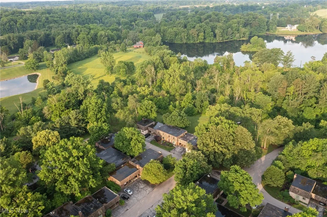 Aerial view of property's location with a large body of water and a heavily wooded area