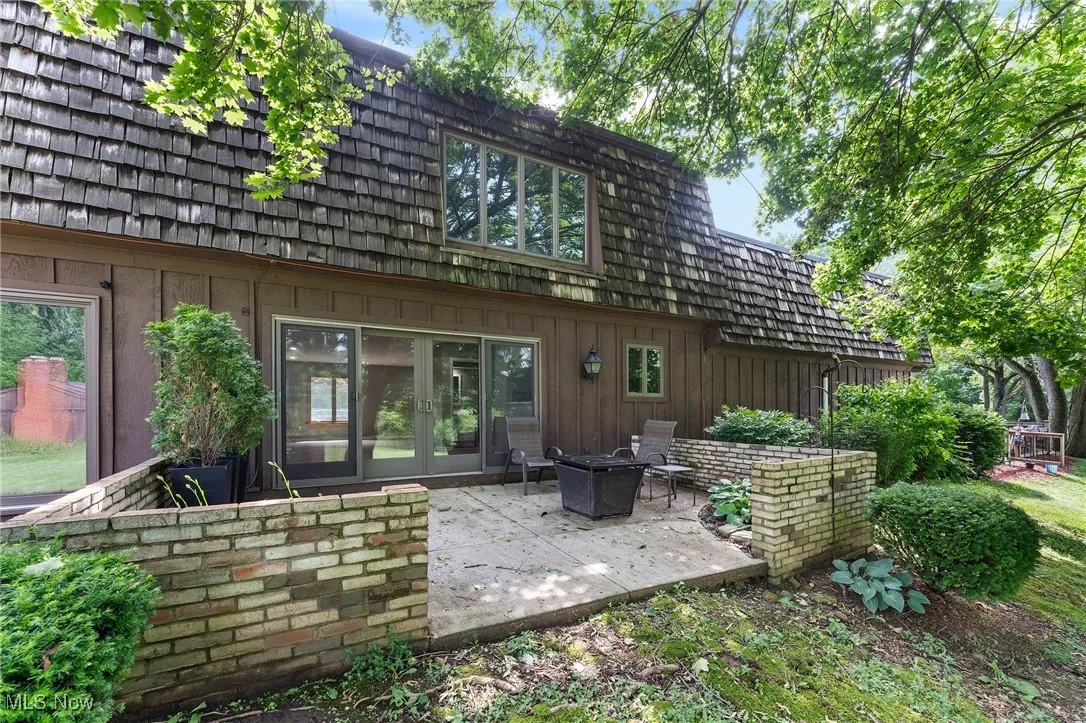 Back of property with board and batten siding, a patio, french doors, and mansard roof