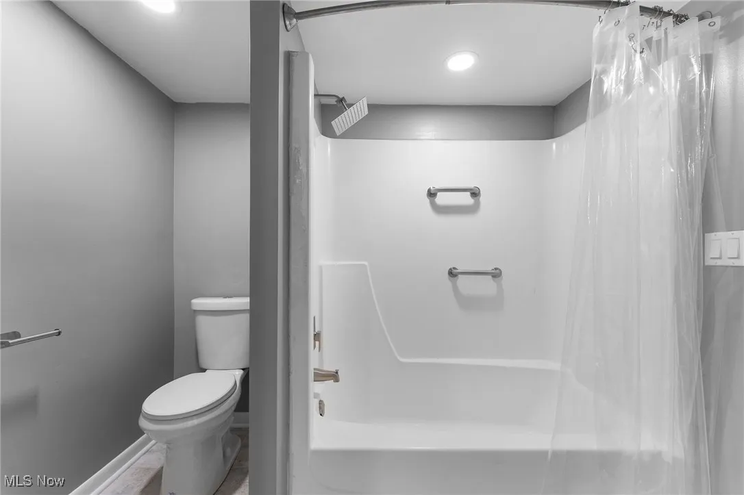 Bathroom with shower / tub combo with curtain and toilet