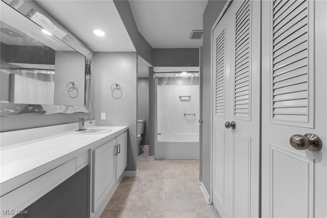 Full bathroom featuring a closet, vanity, shower / bath combination with curtain, and recessed lighting