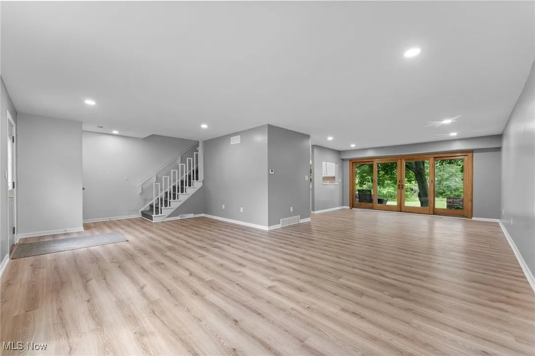 Unfurnished living room featuring recessed lighting, light wood-style floors, and stairs