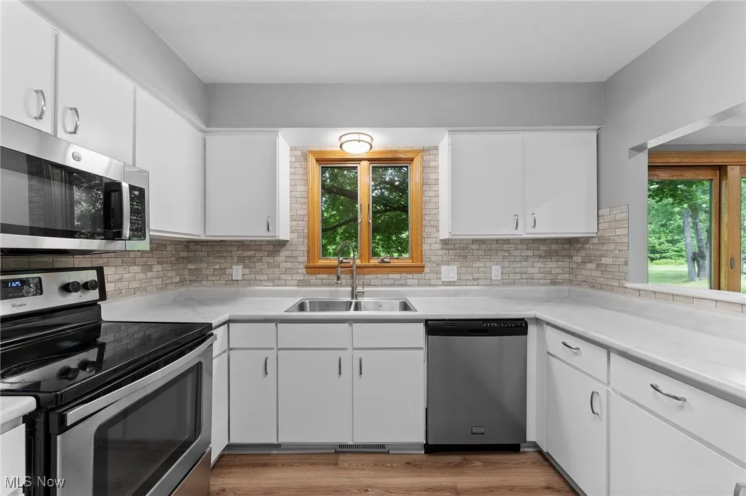 Kitchen with appliances with stainless steel finishes, light countertops, decorative backsplash, and white cabinets