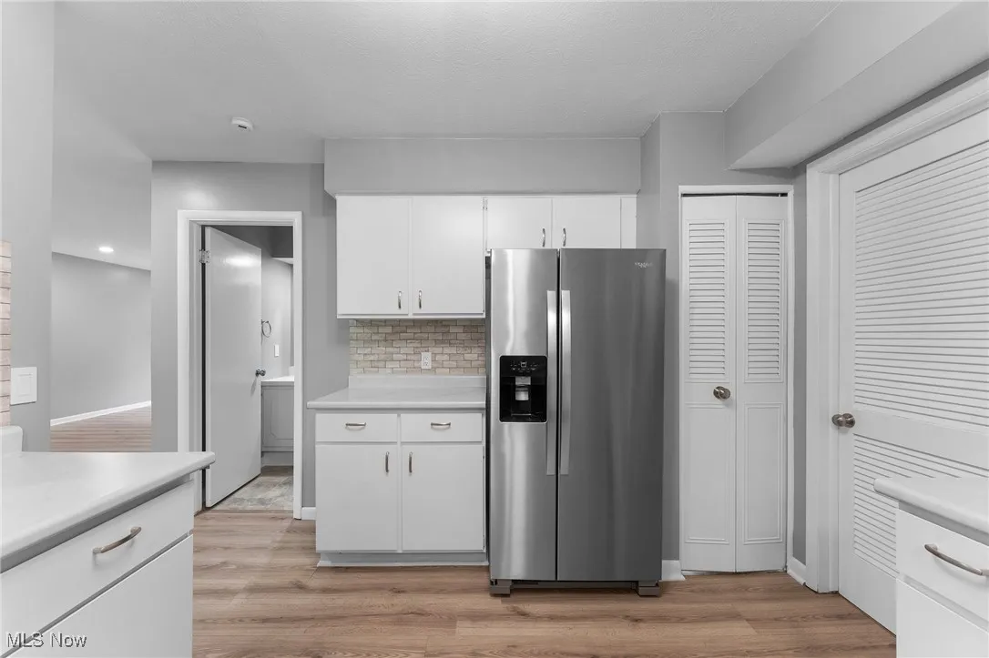 Kitchen featuring stainless steel fridge with ice dispenser, light countertops, and light wood-style floors