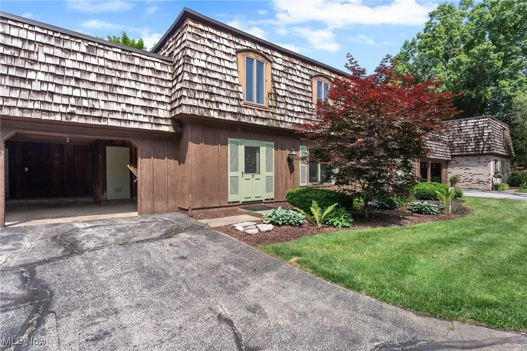 View of front of home featuring mansard roof, asphalt driveway, and a front yard