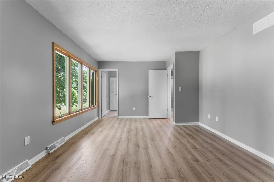 Empty room with light wood-style flooring and a textured ceiling