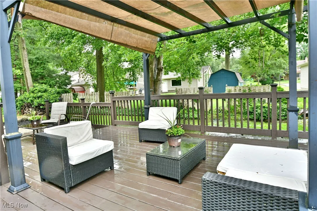 Wooden deck featuring a storage shed and a pergola