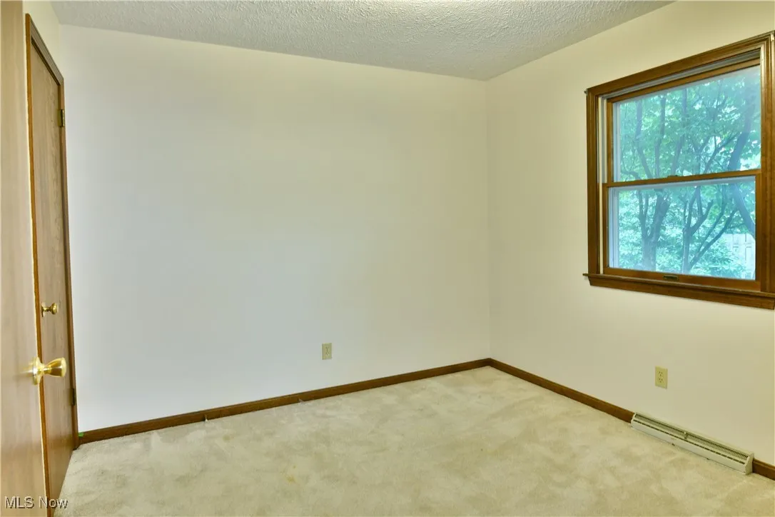 Unfurnished room with a baseboard radiator, carpet flooring, and a textured ceiling