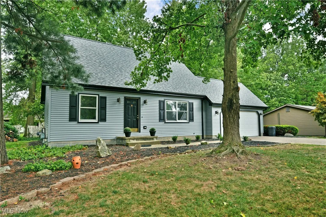 View of front of property featuring roof with shingles, concrete driveway, an attached garage, and a front yard