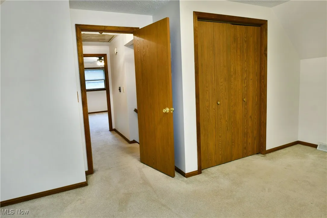 Corridor featuring light colored carpet and baseboards