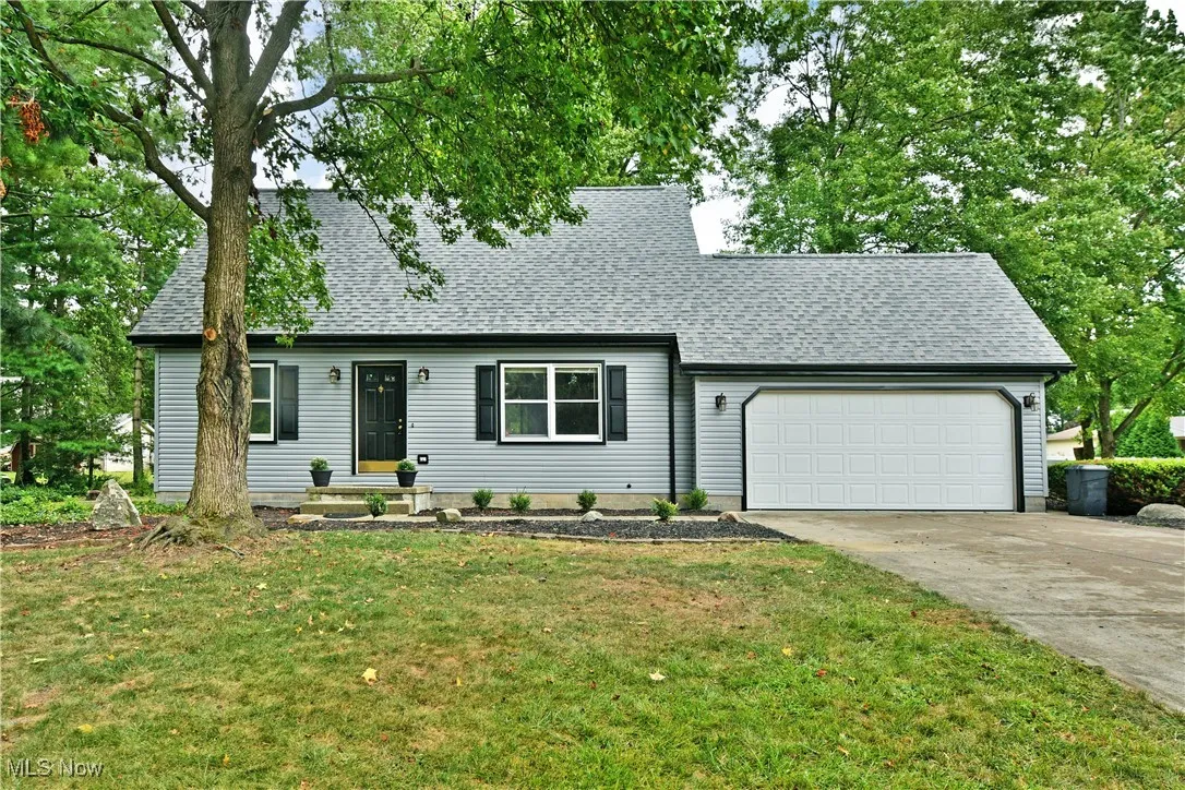 View of front of property featuring concrete driveway, roof with shingles, an attached garage, and a front lawn