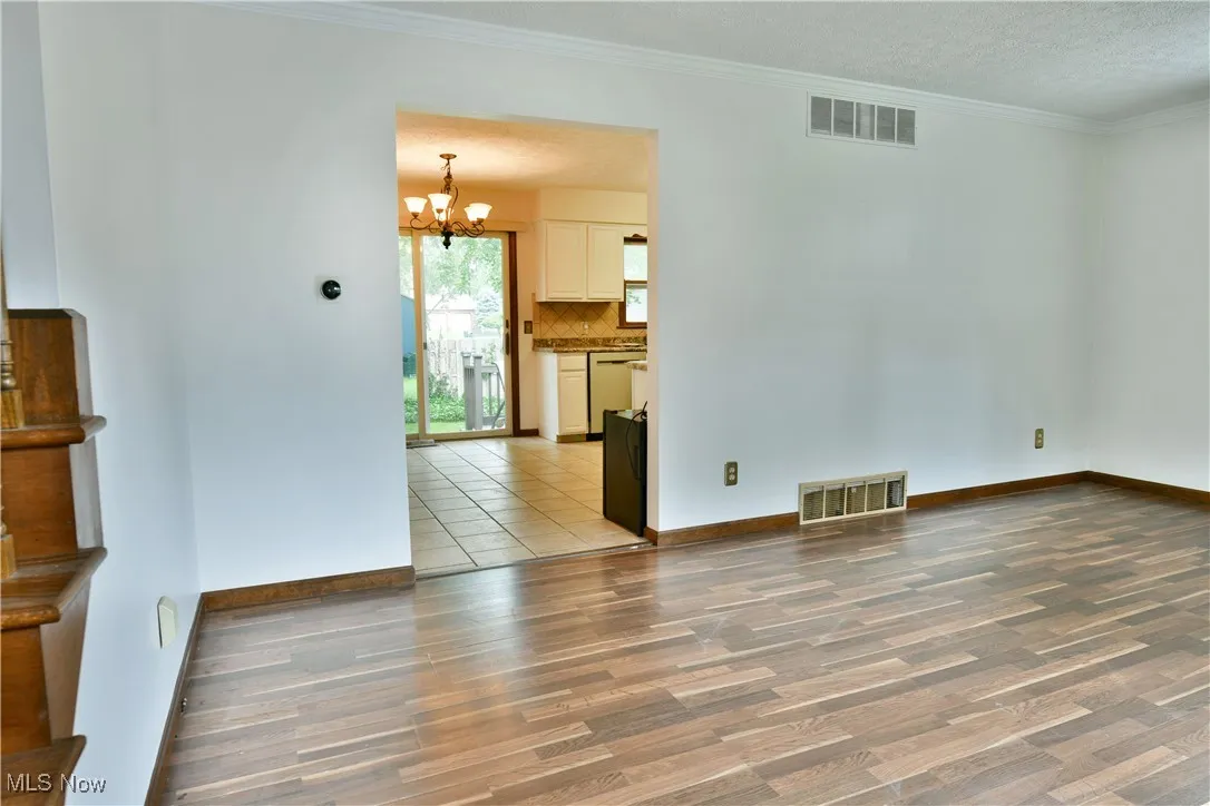Unfurnished room with wood finished floors, a chandelier, and crown molding