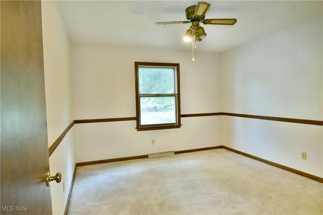 Carpeted spare room with a ceiling fan and baseboards
