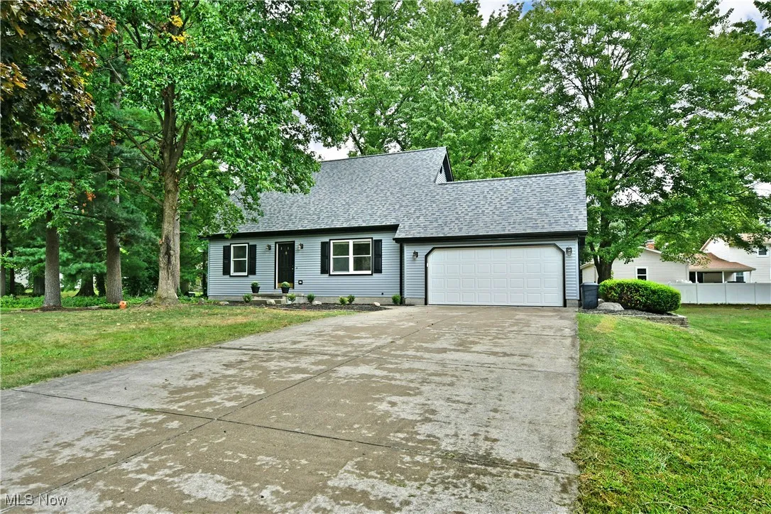 View of front of property featuring a front yard, driveway, roof with shingles, and a garage