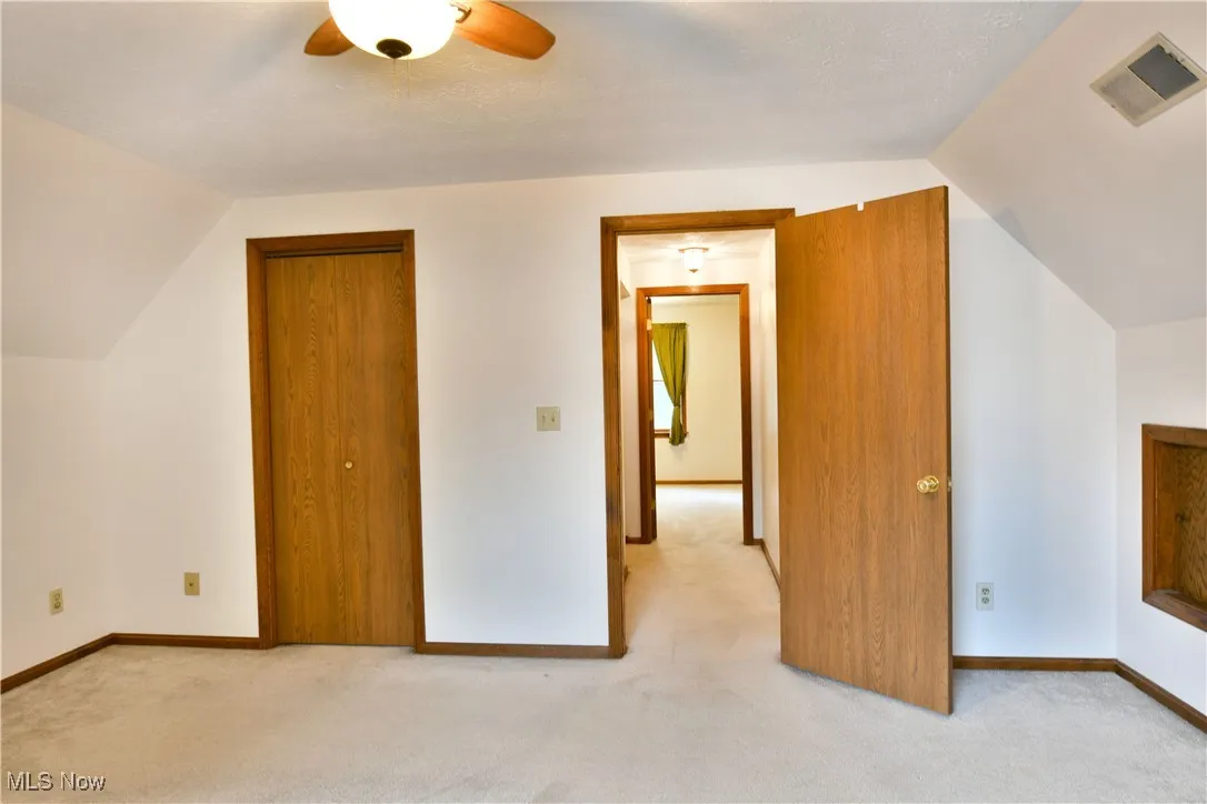 Additional living space with light carpet, a ceiling fan, and lofted ceiling