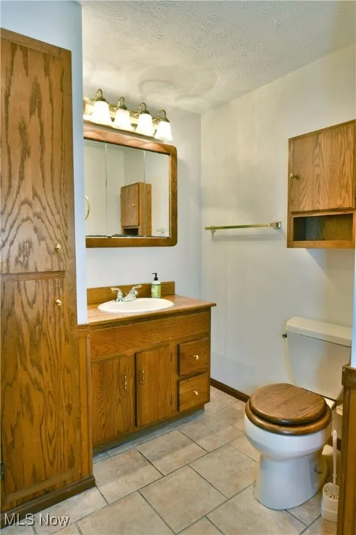 Bathroom with vanity, a textured ceiling, and tile patterned floors