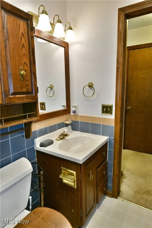 Bathroom with vanity, tile walls, wainscoting, and tile patterned floors