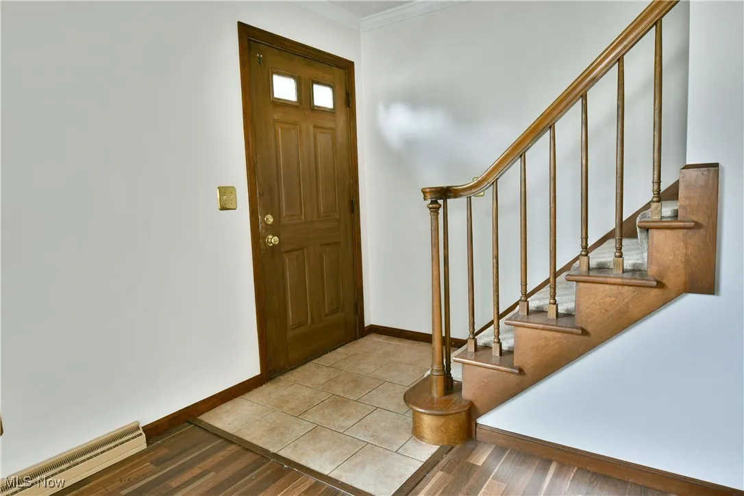 Entryway featuring crown molding, stairway, and wood finished floors