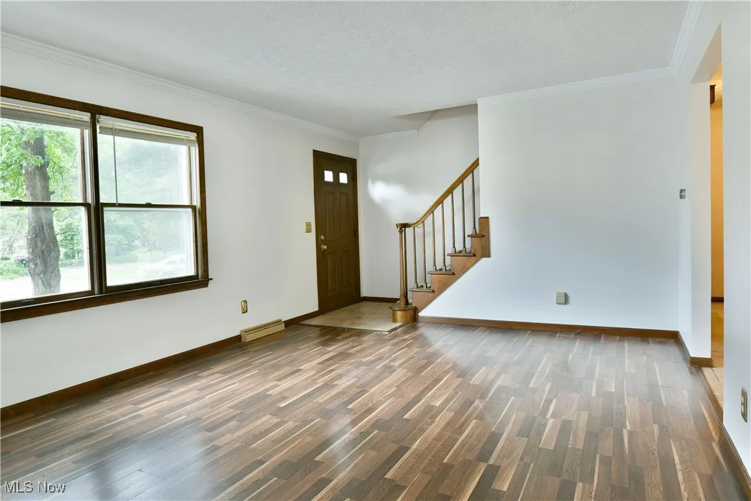 Entrance foyer with wood finished floors, stairs, ornamental molding, and a textured ceiling