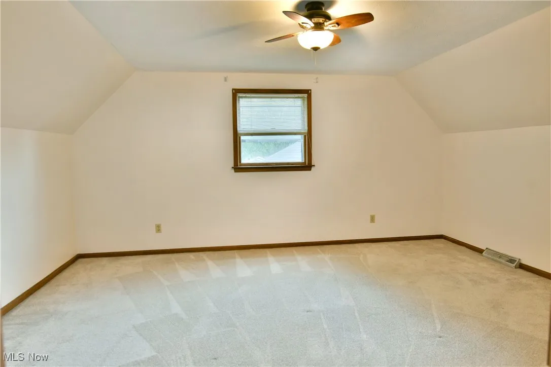 Bonus room with ceiling fan, light carpet, and lofted ceiling