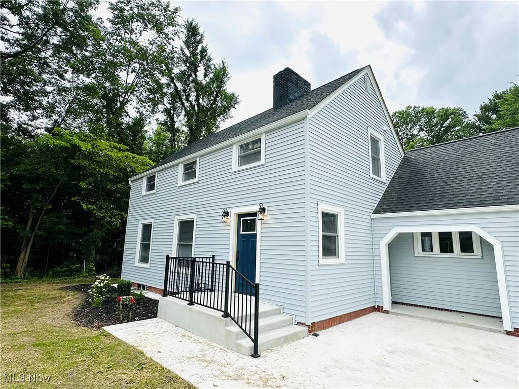Front view of property featuring a chimney, an attached garage, a shingled roof, and concrete driveway