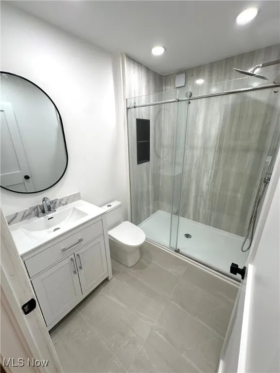 Modern bathroom featuring a new shower stall, vanity, recessed lighting, and tile patterned flooring