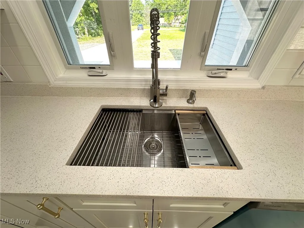 Kitchen view of light granite countertops & modern chefs deluxe sink.
