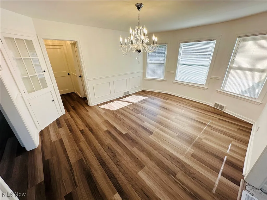 Unfurnished dining area featuring a chandelier and wood luxury vinyl floors