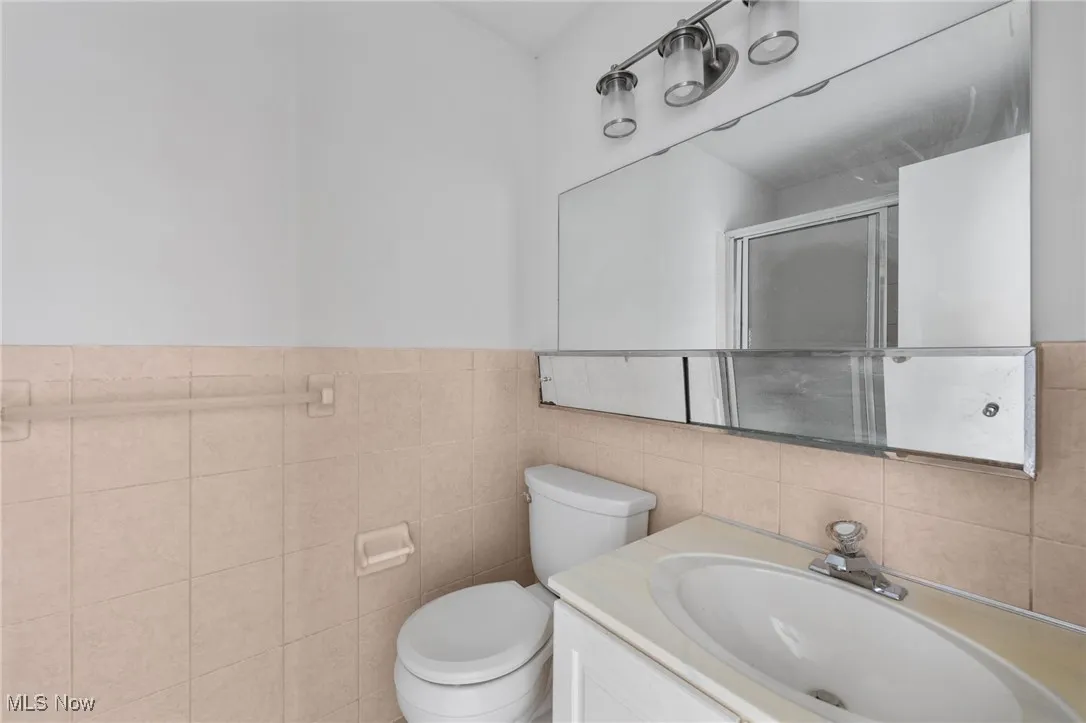 Full bathroom featuring tile walls, vanity, and a stall shower