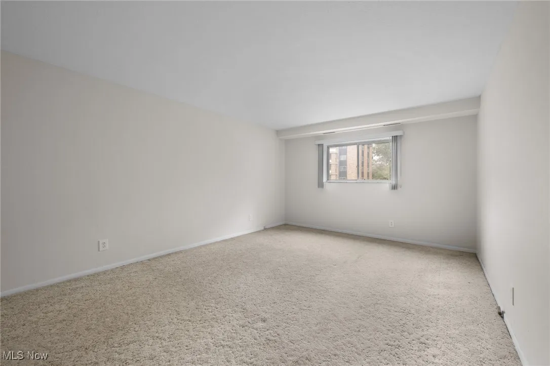 Carpeted spare room featuring baseboards