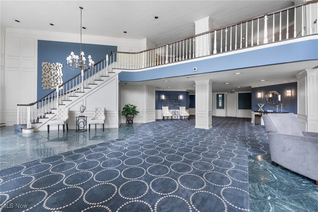 Community lobby featuring a decorative wall, a towering ceiling, ornamental molding, stairway, and recessed lighting