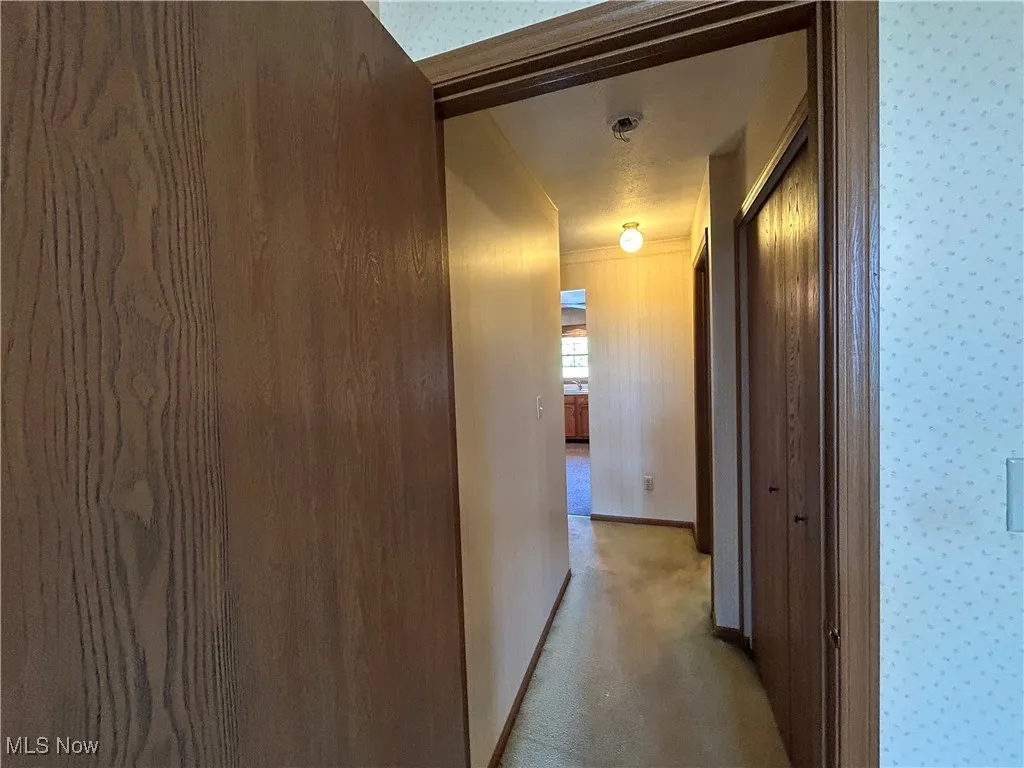 Hallway with wallpapered walls and light colored carpet