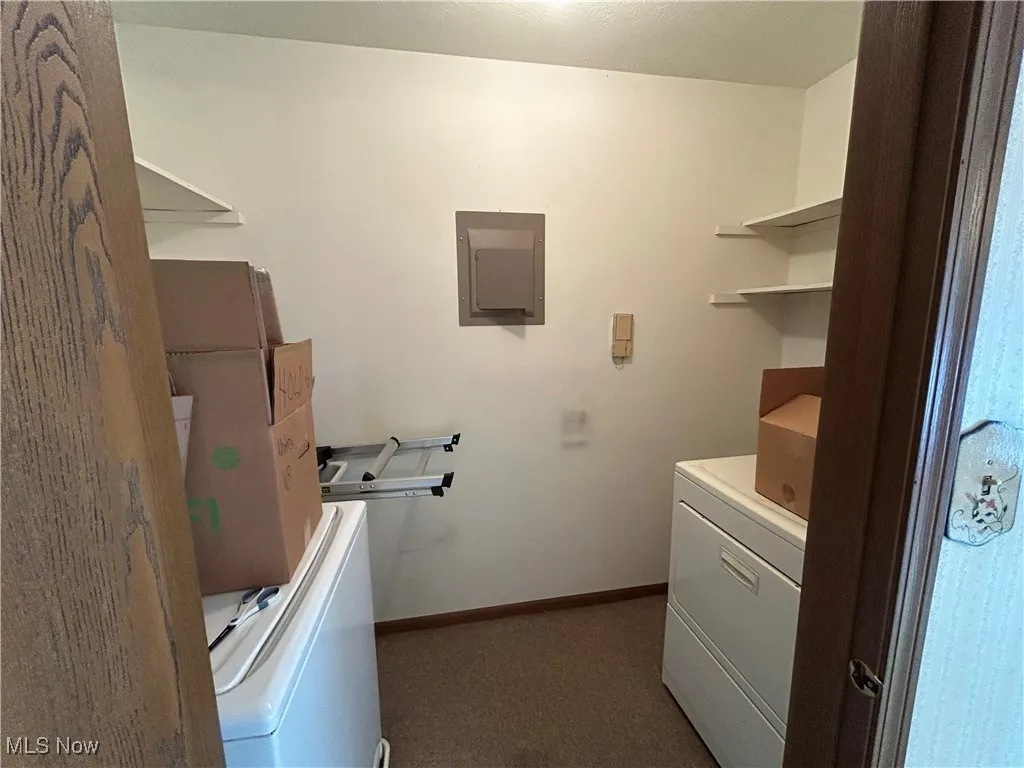 Laundry room with utility sink, electric panel, washer / dryer, and storage shelves