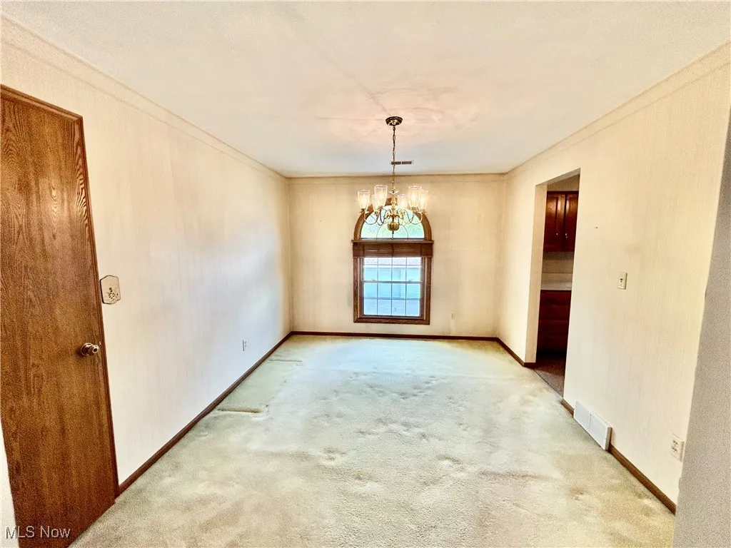 Carpeted dining room with a chandelier