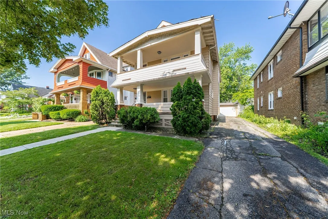View of front of house featuring a porch, an outdoor structure, a front yard, a garage, and a balcony