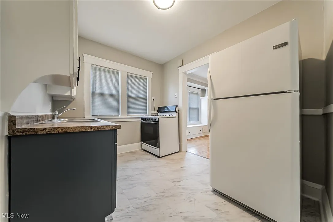 Kitchen featuring white appliances, light marble finish flooring, and white cabinets