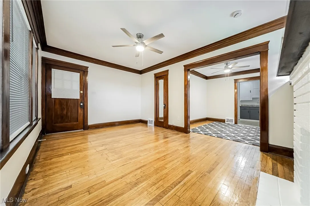 Empty room with a ceiling fan, light wood-style floors, ornamental molding, and a smoke detector