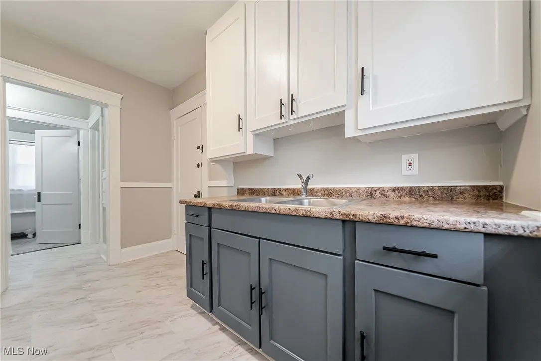 Kitchen with light marble finish floors, gray cabinetry, and white cabinets