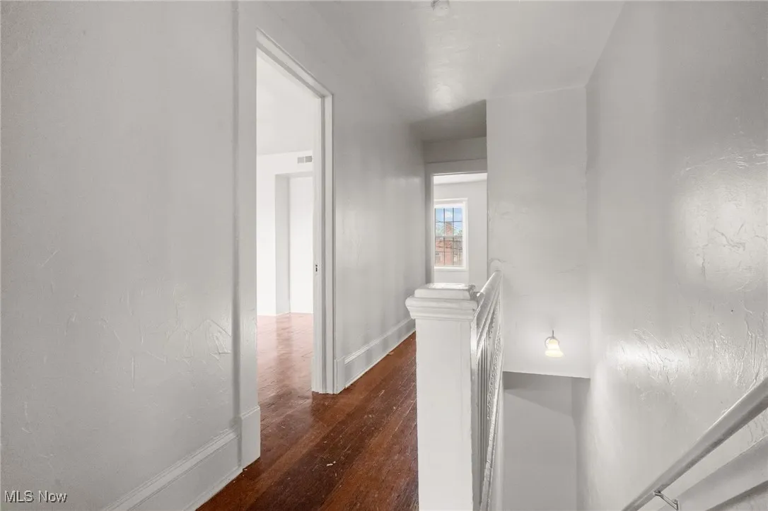 Corridor featuring dark wood-style floors and an upstairs landing