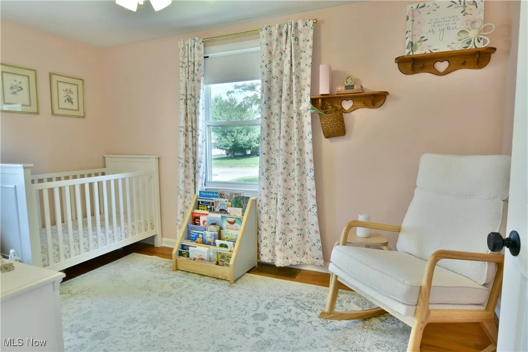Bedroom with a nursery area and wood finished floors
