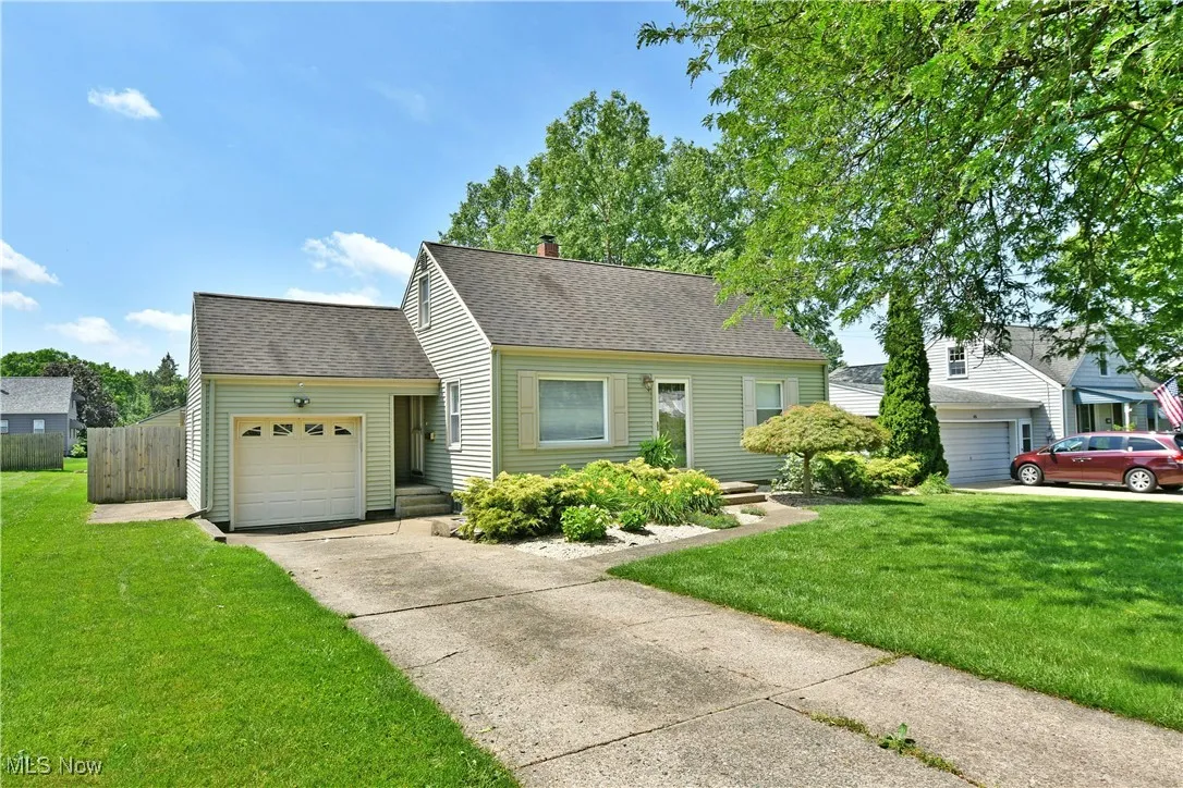 View of front of home featuring an attached garage, a shingled roof, driveway, and a chimney