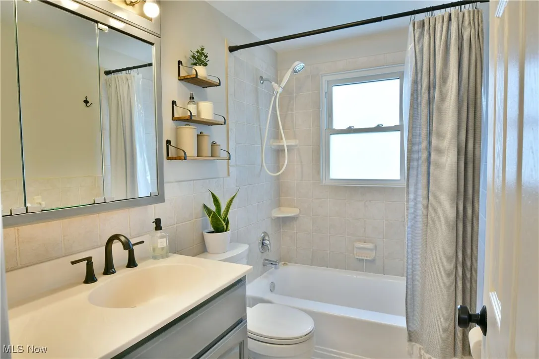 Bathroom featuring shower / tub combo, vanity, and tile walls