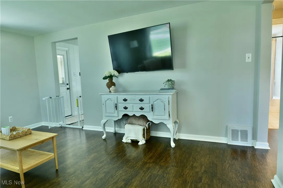 Living area featuring dark wood-style floors and baseboards