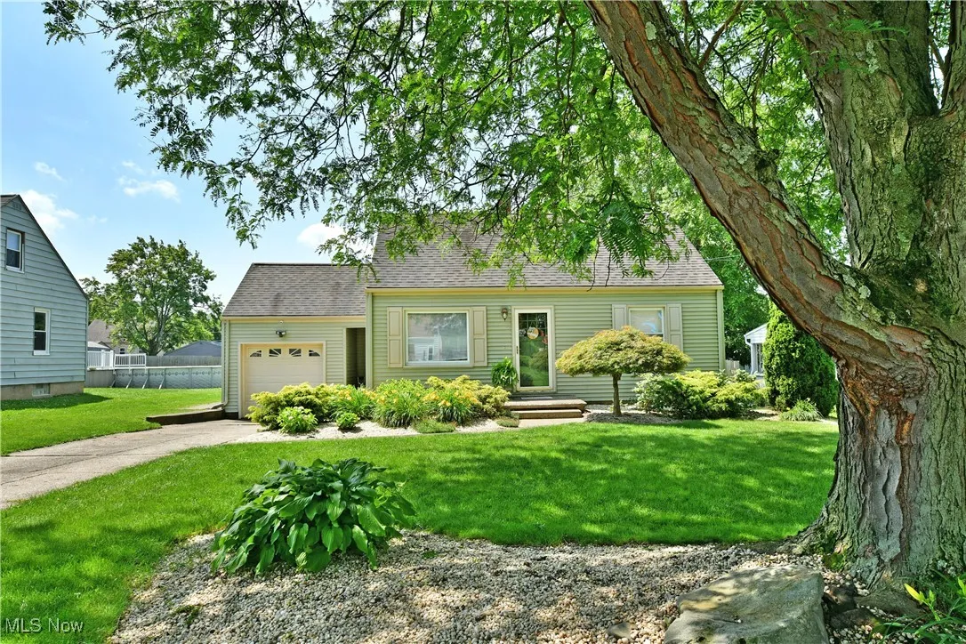New england style home with concrete driveway, an attached garage, and a shingled roof
